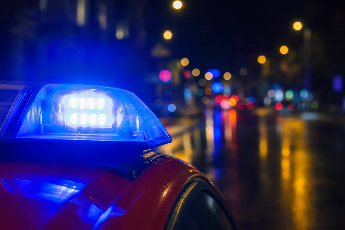 Gyrophare bleu allumé d&rsquo;un véhicule de secours dans une rue mouillée de nuit