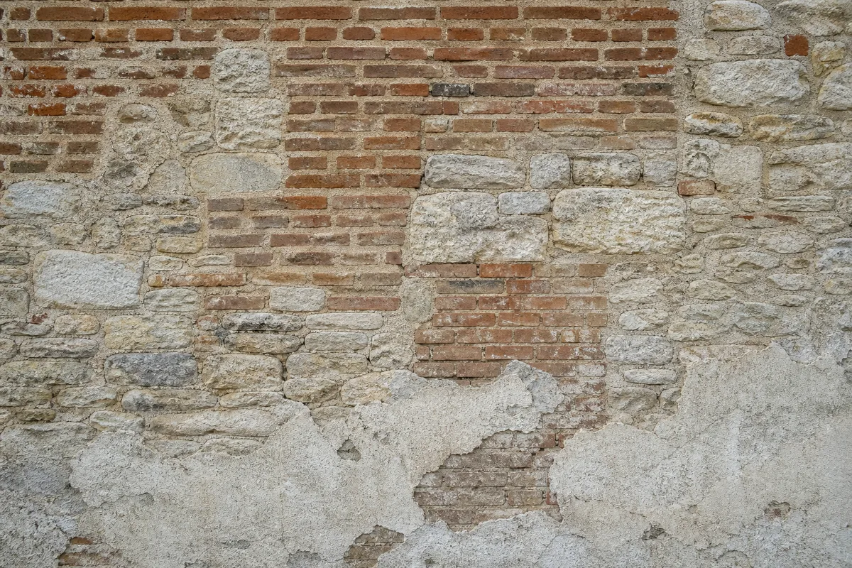 Mur ancien de brique et de moellons portant des reprises de maçonnerie de teintes différentes