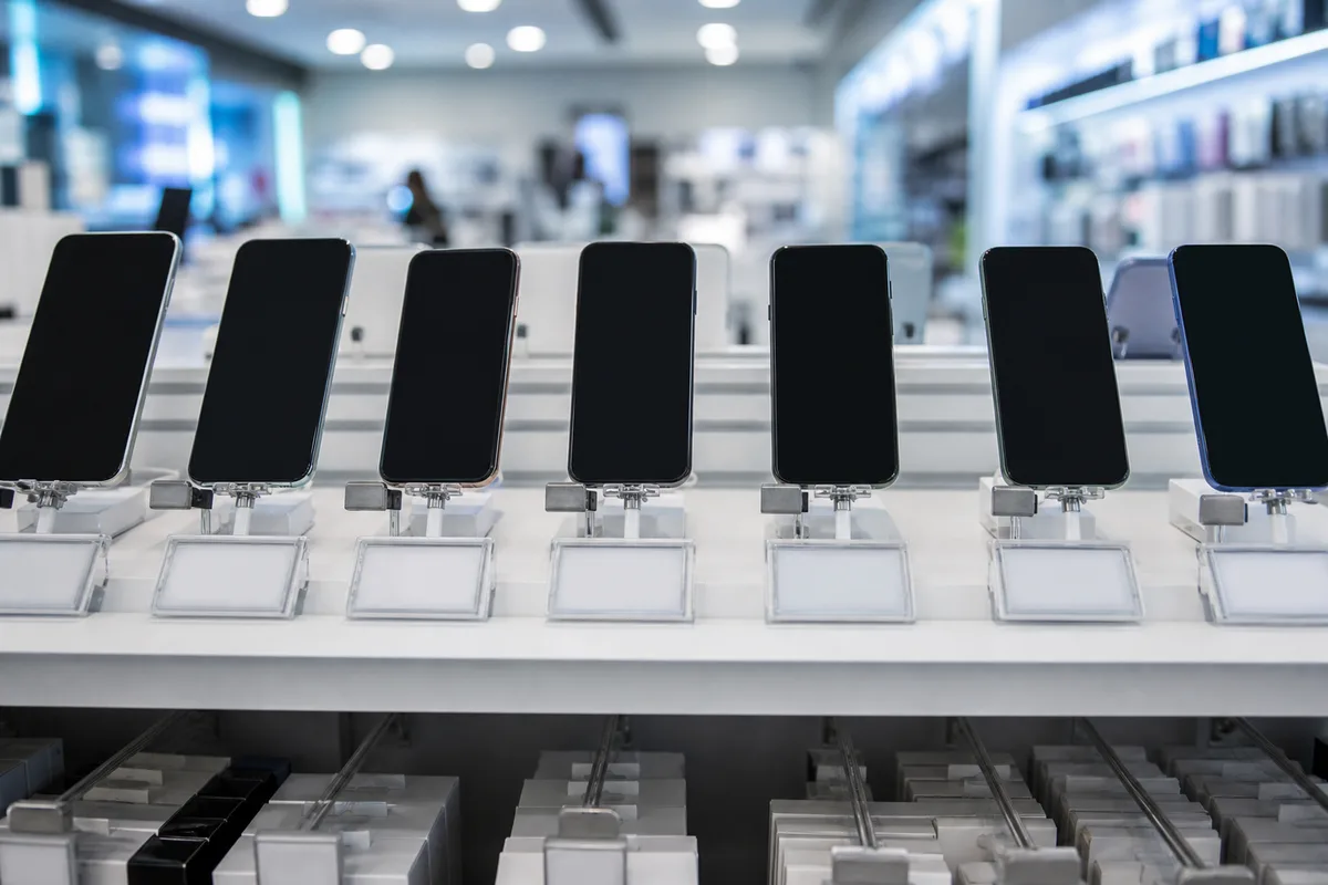 Rayon de téléphonie dans un magasin français avec étiquettes techniques affichées sous les appareils