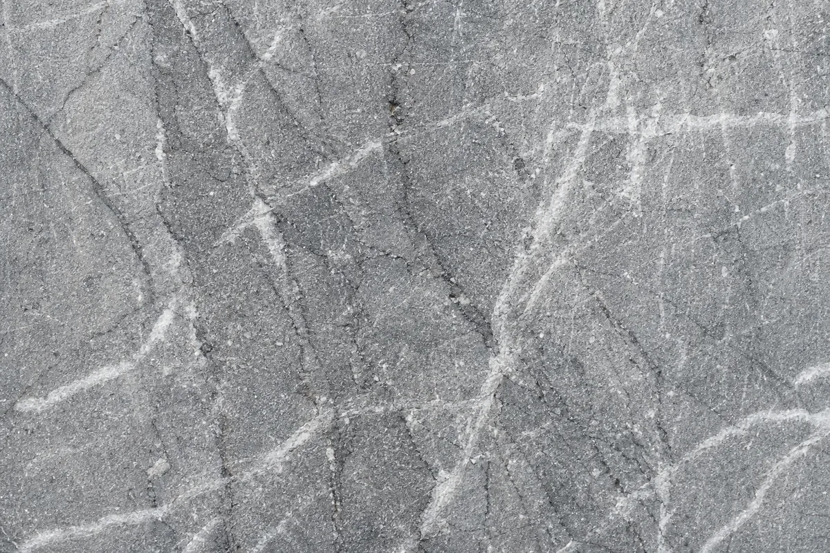 Bloc de marbre gris traversé de veines blanches irrégulières en plan serré