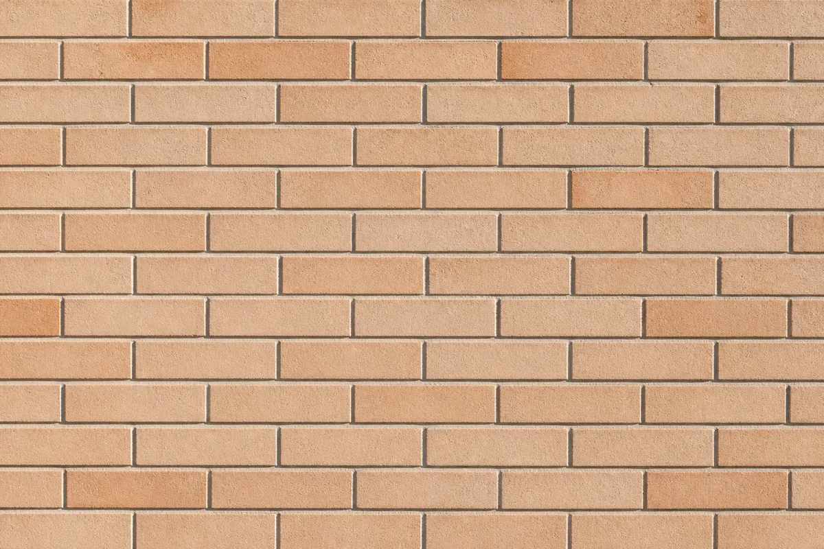 Mur de briques claires appareillées en rangs réguliers, lumière latérale douce